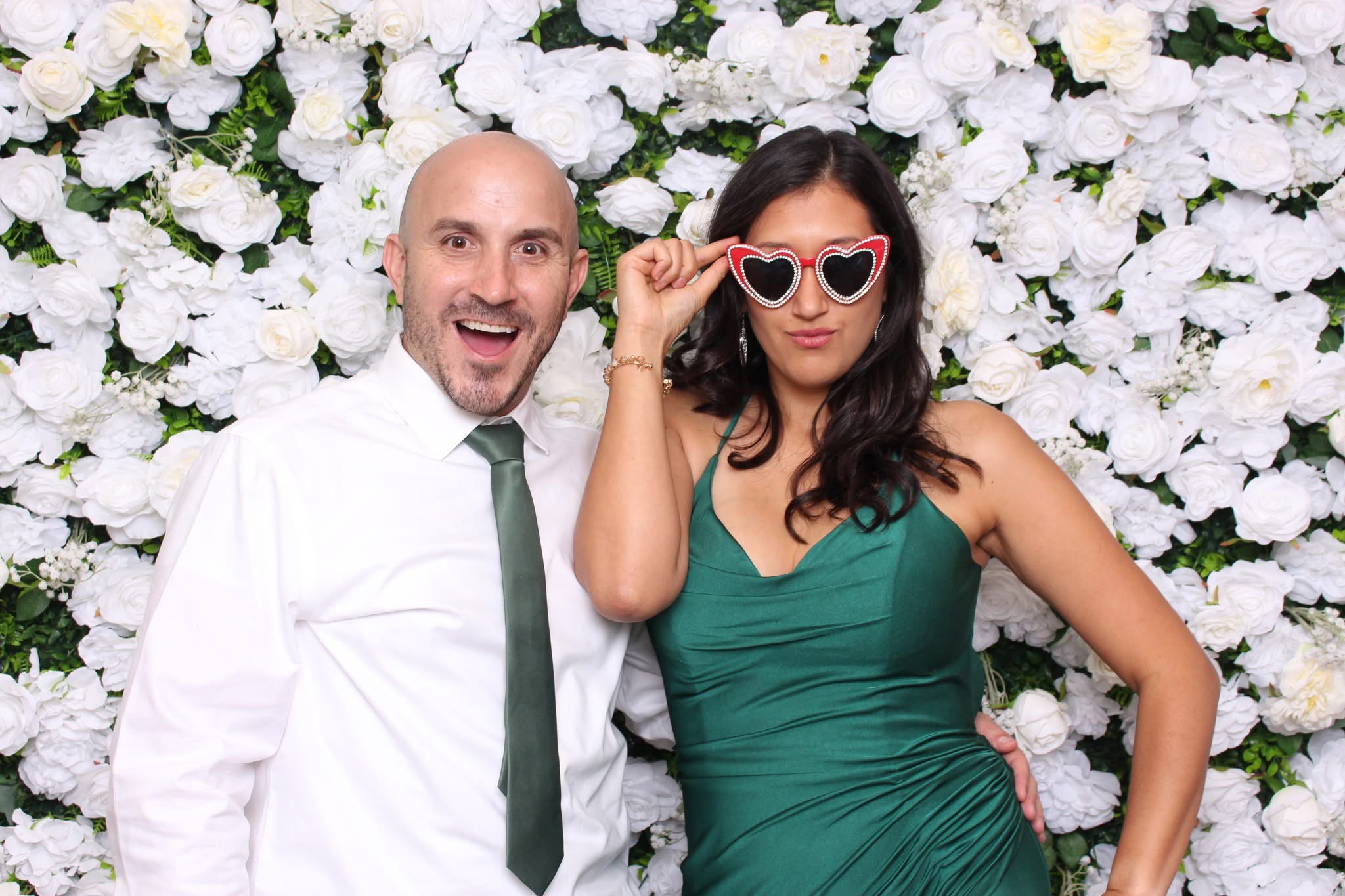 Couple posing in front of white flower wall
